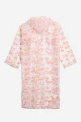 Piloto impermeable de corte recto y largo midi, con capucha ajustable mediante cordones. Presenta un diseño estampado con motivos botánicos en tonos verdes y amarillos sobre una base translúcida. Cuenta con cierre frontal mediante botones a presión y mangas largas.