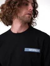 Remera negra de algodón peinado con cuello redondo y mangas cortas, con logo reflectante de Caterpillar en el pecho izquierdo.