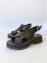Sandalias negras de cuero con tiras cruzadas, plataforma track y hebilla lateral.