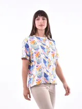 Remera de manga corta color beige con estampado de bananas en tonos amarillo, naranja y rosado.