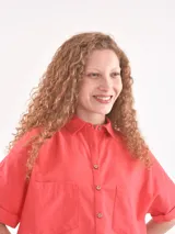 Camisa de manga corta, color rojo, con cuello camisero y botones frontales. Presenta dos bolsillos de parche en el pecho.