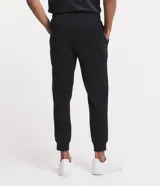 Pantalón deportivo de corte jogger, color negro, con cintura elástica ajustable mediante cordón, bolsillos laterales y puños acanalados en los tobillos. Confeccionado en tejido de algodón con interior felpudo.