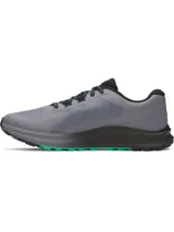 Championes de trail running Under Armour Charged Bandit TR 3, color gris con detalles en negro y verde. Presentan una parte superior de malla técnica para mayor ventilación, refuerzos estratégicos para durabilidad y entresuela Charged Cushioning para máxima amortiguación y respuesta. La suela exterior cuenta con tacos técnicos diseñados para ofrecer una tracción superior en terrenos irregulares.