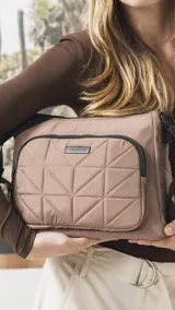 Bandolera de diseño práctico y moderno, confeccionada en tela impermeable color verde militar. Presenta un bolsillo frontal con diseño capitoneado geométrico, cierre principal y bolsillo trasero con cierre. Incluye correa ajustable y detalles en negro.