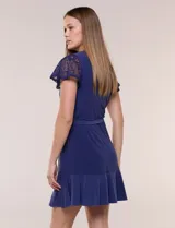 Vestido corto azul de seda fría elastizada, con mangas cortas de encaje calado, lazo para ajustar en la cintura y ruedo con volado plisado.