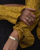 Pulsera tipo esclava abierta con diseño rústico y acabado irregular, fabricada en bronce y alpaca.