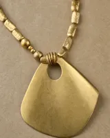 Collar dorado con cuentas texturizadas y un gran dije colgante de forma geométrica irregular.