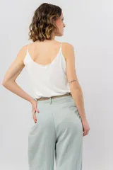 Musculosa de breteles finos con escote en V, confeccionada en tejido fluido con acabado satinado.