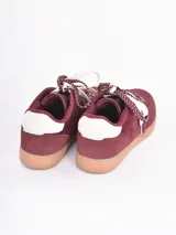 Championes de estilo urbano en color bordó, confeccionados en gamuza con detalles en cuero blanco. Presentan cordones gruesos con estampado de lunares y suela de goma color caramelo.