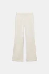 Pantalón flare de tiro alto confeccionado en tejido satinado color negro, con bajo en línea evasé y cierre frontal con cremallera oculta y gancho metálico.