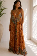 Vestido largo de calce amplio y fluido, con escote en V y tiras regulables en los hombros. Presenta una combinación de estampado animal print con detalles paisley en tonos azules y turquesa.