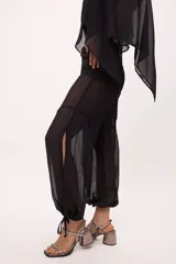 Pantalón ancho de seda color amarillo, estilo parachute o globo, con talle alto y cordones ajustables en los tobillos.