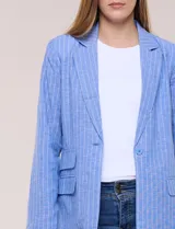 Blazer de lino y algodón color beige con diseño de rayas diplomáticas blancas, solapa clásica, cierre de un botón frontal y bolsillos laterales con solapa.