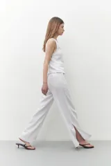 Pantalón blanco de lino, de corte ancho y con tajo lateral en el ruedo.