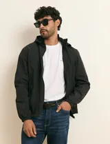 Campera impermeable gris con capucha, cierre frontal y bolsillos laterales con cremallera.