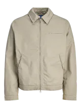Campera tipo worker de color beige, con cuello camisero, cierre frontal completo y bolsillos laterales. Presenta un diseño minimalista y funcional con acabado limpio.
