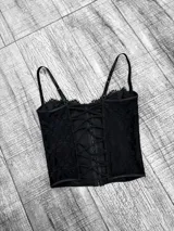 Corset negro de encaje con escote corazón, ballenas y breteles finos regulables.