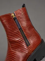 Bota corta de cuero con textura tipo crocco en color chocolate, con suela track negra de goma y cierre lateral.