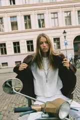 Chaqueta marrón de efecto ante con cuello solapa, manga larga, bolsillos delanteros de plastrón, cierre frontal con botones y cinturón a juego.