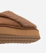 Pantufla abierta de diseño acogedor, confeccionada en poliéster con acabado tipo gamuza y forro de piel sintética. Presenta una suela alta de goma termoplástica que proporciona estabilidad y confort.