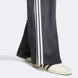 Pantalón deportivo Adidas Satin Loose de corte holgado, color negro con las icónicas tres tiras blancas a los lados y el logo del trifolio bordado. Confeccionado en tejido satinado con diseño de perneras anchas.
