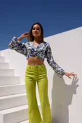 Blusa corta de algodón con estampado de hojas en tonos azul, blanco y verde. Tiene escote en V y mangas largas con puños acampanados.