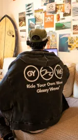 Campera con capucha y cierre frontal, confeccionada en algodón con efecto de lavado desgastado color negro. Presenta bordado frontal con la frase 'Classy Waves' y detalle bordado en la manga.