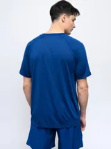 Remera deportiva de entrenamiento Umbro modelo Zest, color azul con diseño texturizado de líneas horizontales y mangas cortas raglán. Logo de la marca estampado en el pecho.