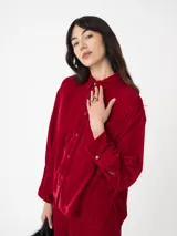 Camisa corta negra de terciopelo, de silueta cuadrada oversized, con bolsillo delantero y detalle en los puños y cuello con botón oro en forma de flor.