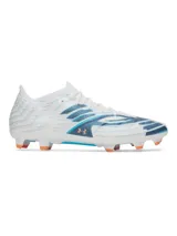 Championes de fútbol Under Armour Shadow Pro 4 FG, diseñados para césped natural. Presentan un empeine textil ligero en color blanco con detalles gráficos en azul y logo de la marca en tono cobrizo. Cuentan con cuello y lengüeta de punto para un ajuste tipo calcetín, contrafuerte 3D en el talón y una suela con tacos biomecánicos para optimizar la aceleración y desaceleración.