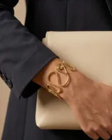 Brazalete rígido de acero con baño de oro, con diseño de ondas entrelazadas y acabado texturizado.