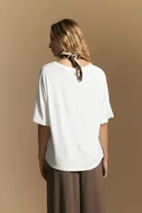 Remera de calce relajado con silueta fluida, confeccionada en tejido de viscosa con elastano. Presenta cuello redondo, mangas cortas y un diseño minimalista de caída suave.