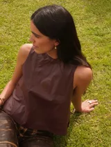 Chaleco de gamuza negro, sin mangas, con cuello redondo y diseño bordado de un sol en el pecho.