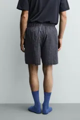 Set de pijama compuesto por una remera lisa de manga corta con cuello redondo y una bermuda a cuadros con bolsillos laterales y cintura elástica.