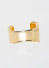 Pulsera brazalete rígido dorado con diseño ondulado.