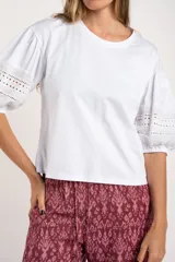 Remera negra de algodón con mangas tres cuartos abullonadas y detalle de bordado calado tipo ojal en la zona del antebrazo.