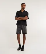 Bermuda masculina de corte recto confeccionada en denim de algodón, con cintura fija, trabillas para cinturón, cierre tradicional y bolsillos laterales y traseros.