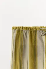 Pantalón ZARA Woman Collection confeccionado en mezcla de lyocell, con diseño de rayas verticales en tonos verde oliva y beige. Presenta tiro medio, cintura ajustable con cordón y perneras rectas.