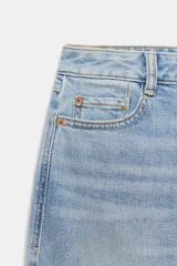 Jeans de tiro medio y corte relaxed fit, color azul con efecto deslavado, diseño de cinco bolsillos y bajo vuelto. Cuenta con cierre frontal de cremallera y botón metálico.