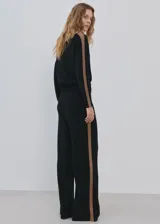 Pantalón de punto negro con diseño recto y holgado, con una franja lateral en tono marrón.