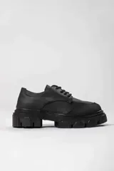 Zapato acordonado de cuero negro con suela track.