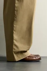 Mocasín de vestir de cuero color marrón, con diseño tipo antifaz en el empeine, costuras visibles en la puntera y suela a contraste.