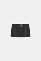 Falda pantalón de tiro medio con diseño de rayas verticales. Presenta un cinturón integrado con hebilla metálica y cierre lateral con cremallera oculta.