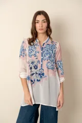 Túnica blanca de seda con bordados florales en azul y rojo, cuello mao con botones y mangas largas.