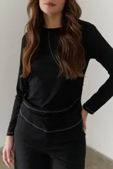 Remera blanca de manga larga con cuello redondo y costuras decorativas en contraste de color negro.