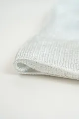 Poncho de tejido ligero con acabado brillante y flecos en los extremos.
