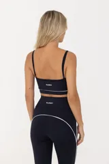 Top deportivo negro con breteles finos regulables y contorno inferior blanco.