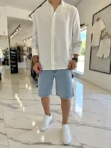 Camisa oversize de lino color blanco, con cuello mao, manga larga y cierre frontal de botones.