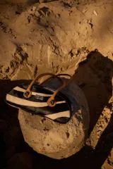 Cartera estilo baguette de cuero con pelo, con estampado animal print a rayas. Presenta una silueta alargada y estructurada, con manijas largas de cuero liso en tono tostado y detalles de nudos esféricos metálicos en la unión de las manijas.