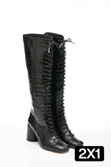 Botas altas de cuero negro con textura tipo cocodrilo, caña alta hasta la rodilla, punta cuadrada y cordones frontales.